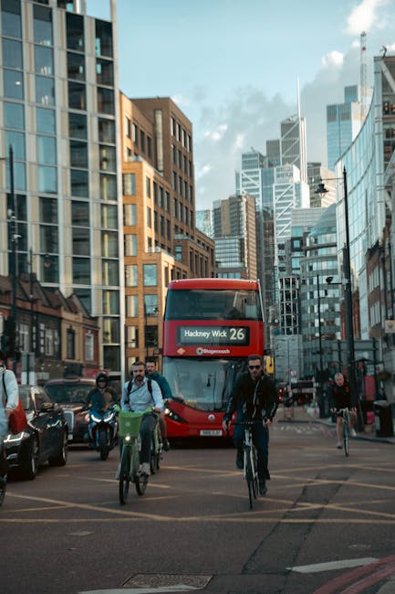 This image features a vibrant street scene in Hackney Wick, showcasing a red double-decker bus displaying the route number 26 on its digital sign, heading towards Hackney Wick station. In the foregrou