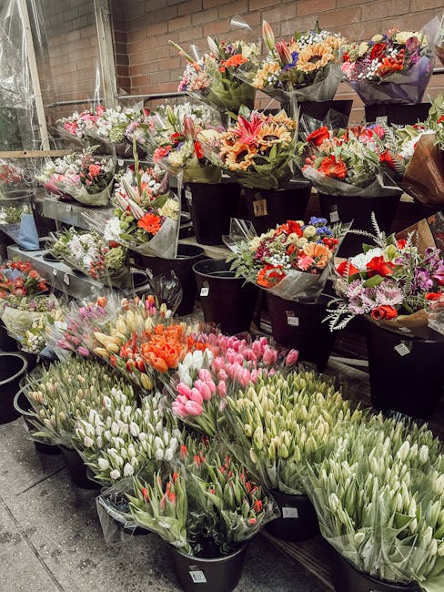 An outdoor display of freshly arranged bouquets and flower bunches at the Wallis Road florist, showcasing a variety of seasonal blooms including pink and white tulips, orange carnations, and mixed flo